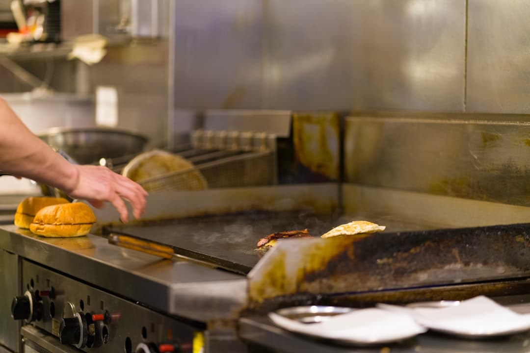 Chef preparing food on a commercial grill.